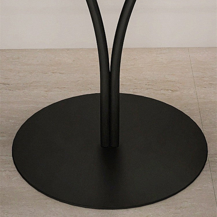 Small Nordic round metal side table beside a reading chair in a bedroom corner
