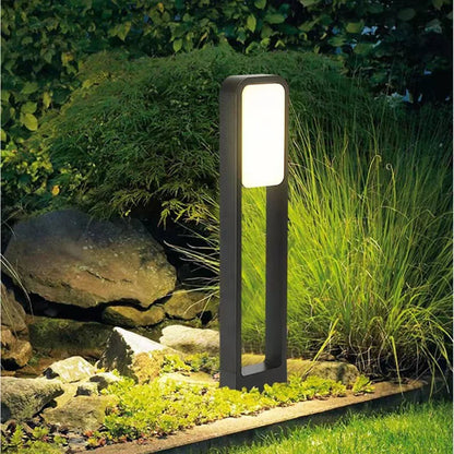 Aluminum lawn lamp glowing in garden at night beside rocks