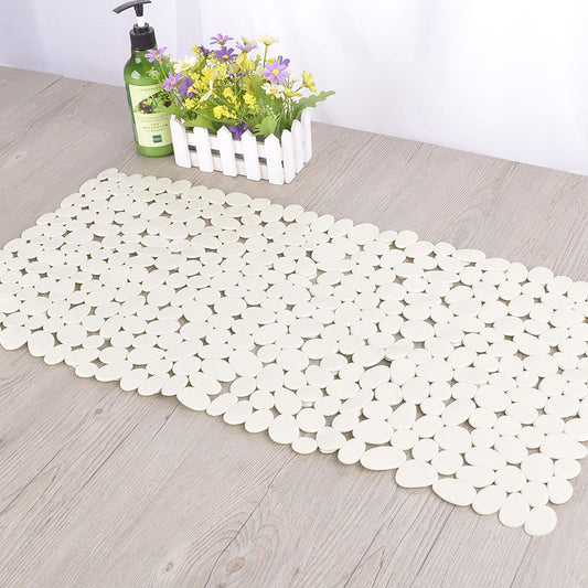 Eco friendly pebble PVC bath mat placed outside a bathtub on white bathroom tile
