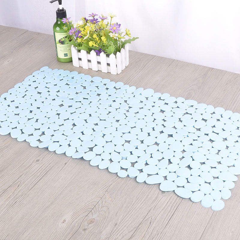 Pebble PVC non slip bath mat being rinsed clean under a shower head in a bathroom

