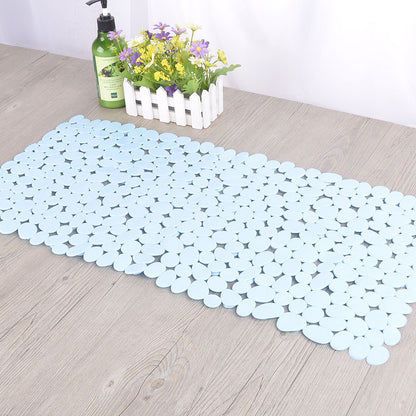 Pebble PVC non slip bath mat being rinsed clean under a shower head in a bathroom
