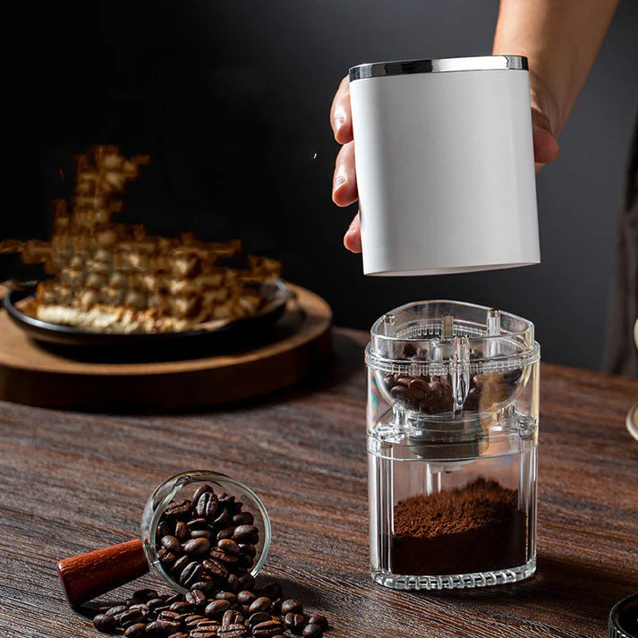 Portable electric coffee grinder on table with coffee beans setup