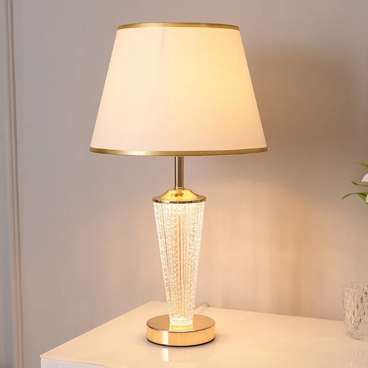 Post modern luxury table lamp gold base white fabric shade in bedroom setting