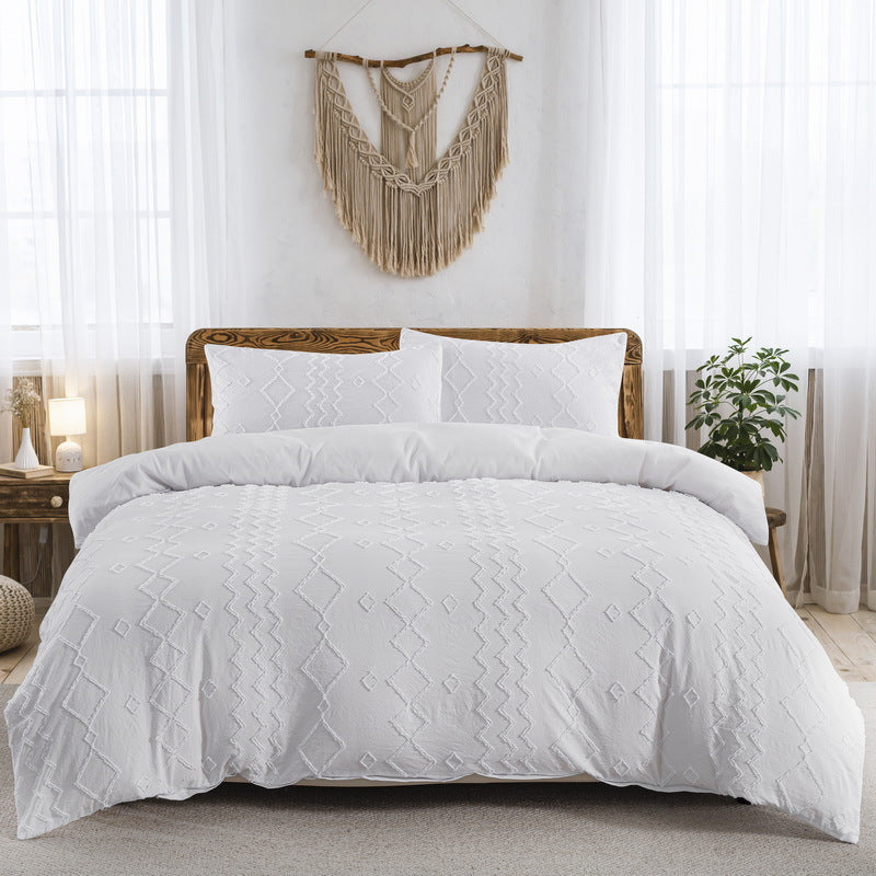 White quilt comforter set on a bed in a bedroom with decorative elements.