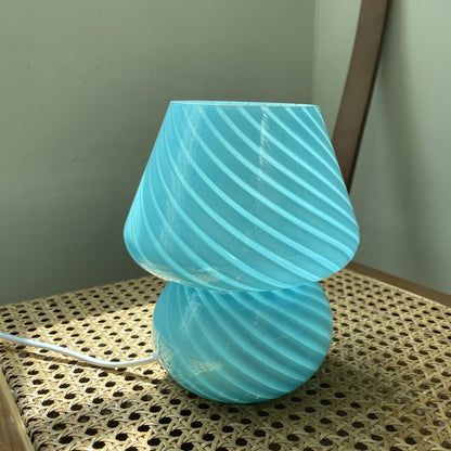 Blue retro glass lamp glowing on a bedroom shelf as a small decorative night light
