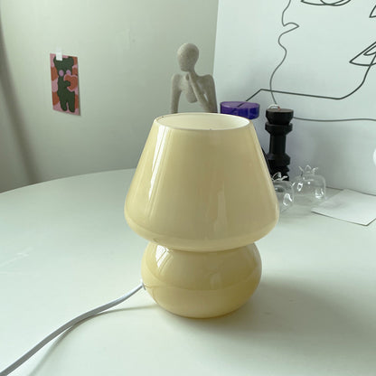 Frosted button pattern retro glass table lamp casting soft diffused light on a desk
