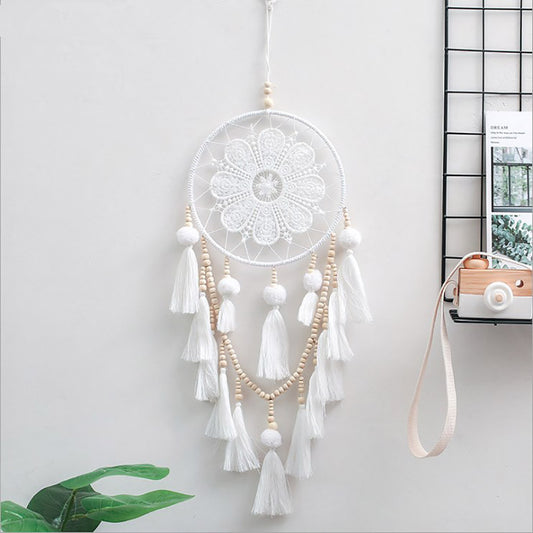 Romantic decorative wall dream catcher with wooden beads and tassel hanging above a bedroom headboard
