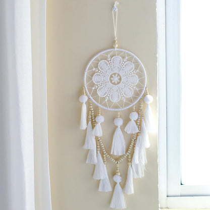 Romantic boho wall dream catcher hanging on a living room wall beside a sofa
