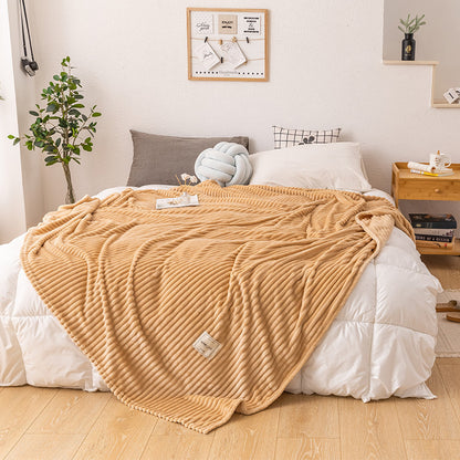 Lightweight plush fleece queen blanket draped over an armchair in a bedroom reading corner
