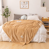 Lightweight plush fleece queen blanket draped over an armchair in a bedroom reading corner