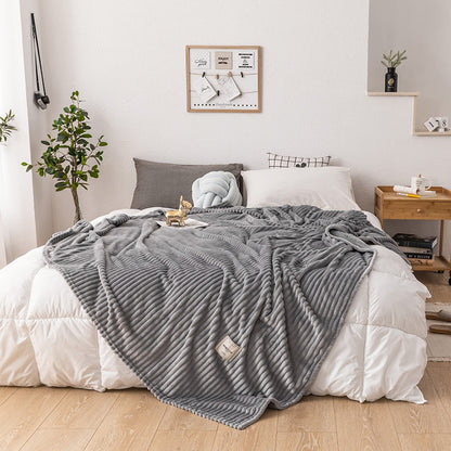 Soft queen size fleece blanket neatly folded at the foot of a guest room bed

