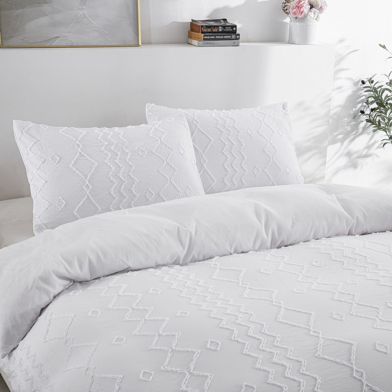 White duvet bedding set on a bed with pillows and a decorative headboard.