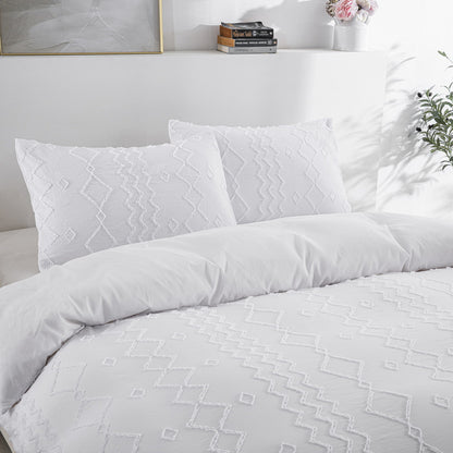 White duvet bedding set on a bed with pillows and a decorative headboard.