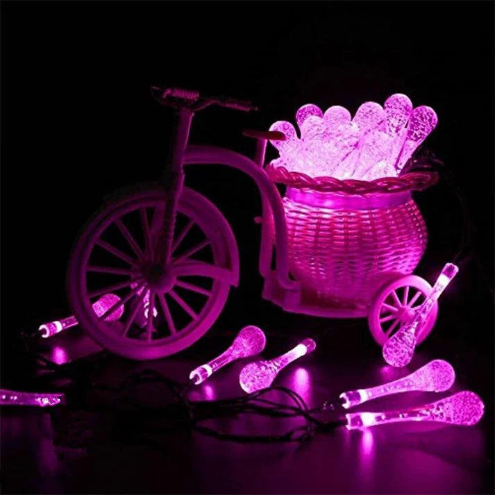 Pink solar water drop string lights in garden at night