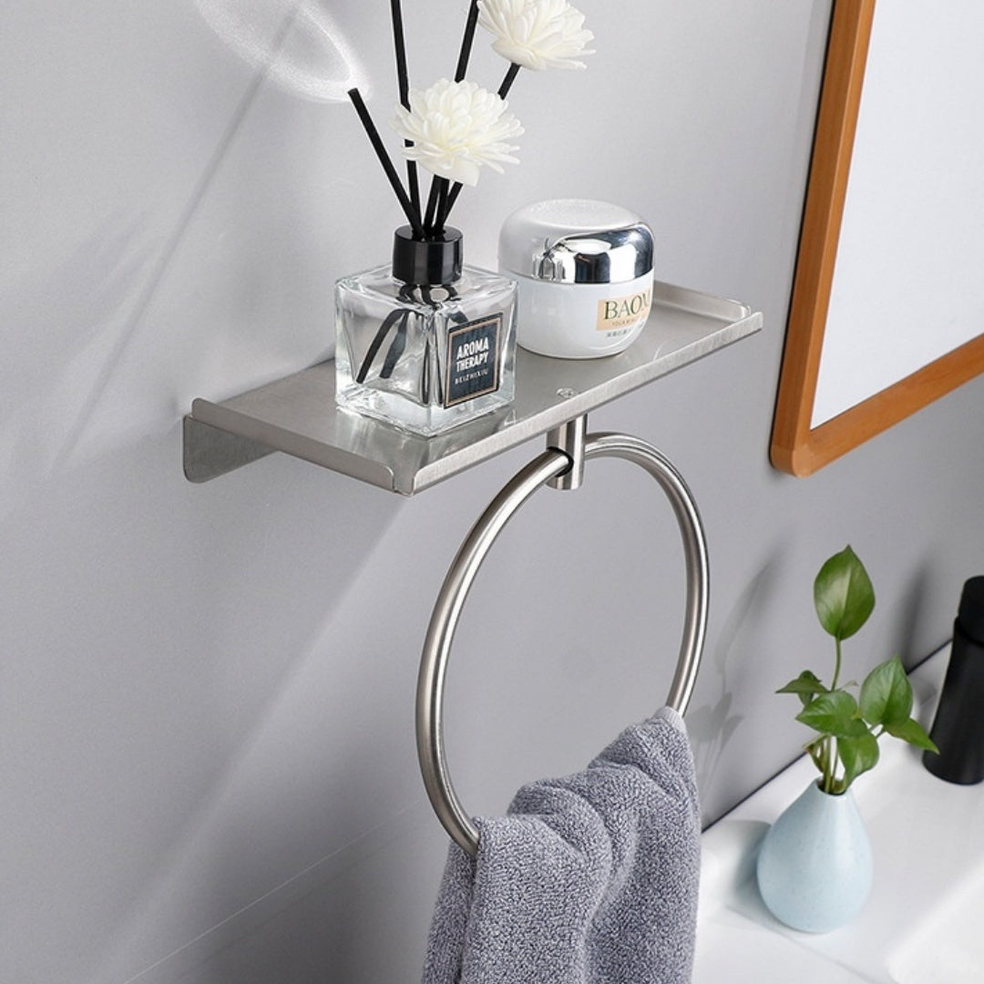 Silver round stainless steel towel ring mounted on a white bathroom wall beside a sink
