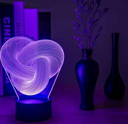 Remote control and touch base of the twist abstract 3D LED night light on a desk
