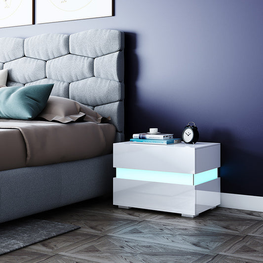 White two drawer bedside side table with RGB LED glow beside a bed in a modern bedroom
