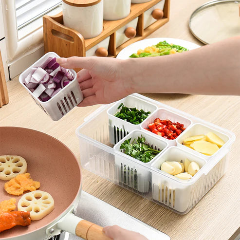 Plastic vegetable keeper box with yellow and green chopped vegetables in compartments