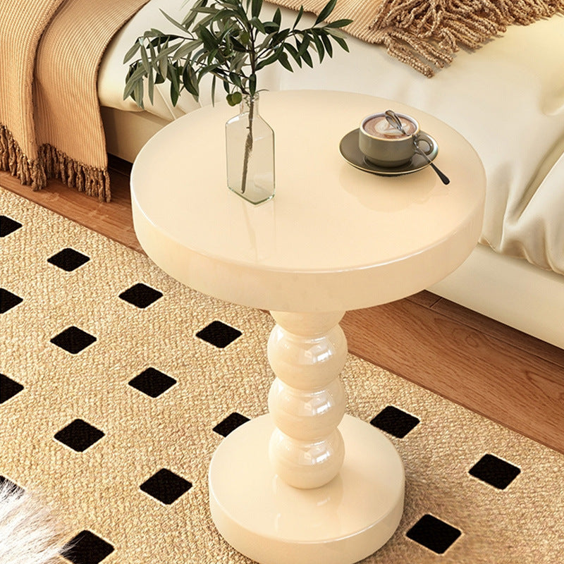 Black vintage solid wood round bedside side table beside a bed in a modern bedroom
