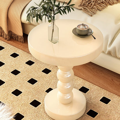 Black vintage solid wood round bedside side table beside a bed in a modern bedroom
