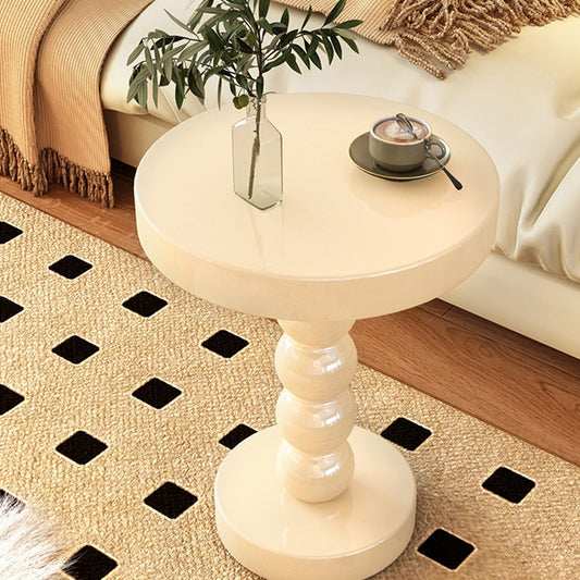 Black vintage solid wood round bedside side table beside a bed in a modern bedroom
