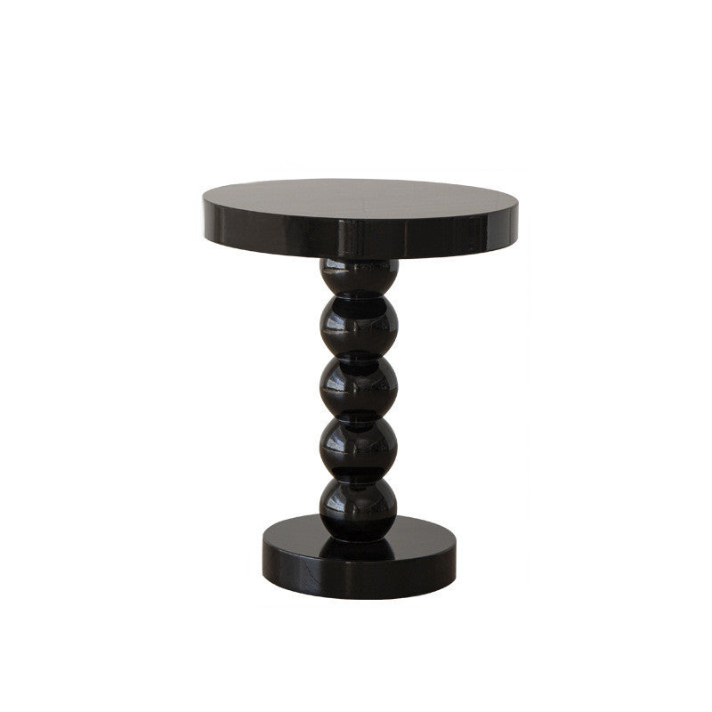 Vintage solid wood round side table holding a lamp, book, and phone as a bedside surface
