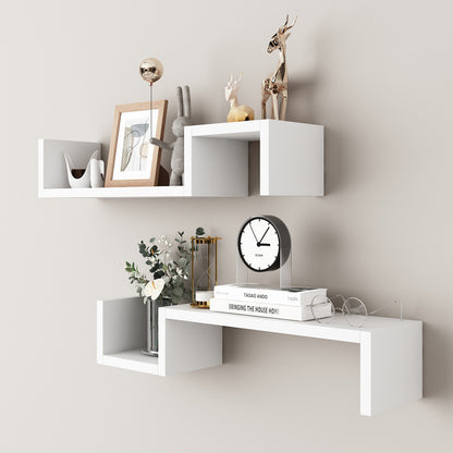 White two layer wall mounted shelf in a living room holding candles and a small frame