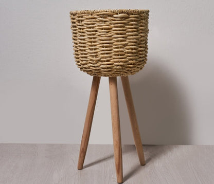 Medium woven straw floor pot on a balcony beside a chair with a green plant inside
