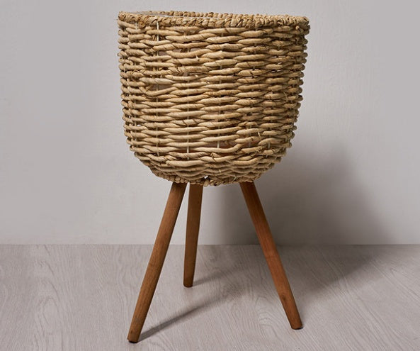 Woven straw floor planter in a Nordic minimalist living room with white walls and wood furniture
