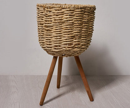 Woven straw floor planter in a Nordic minimalist living room with white walls and wood furniture
