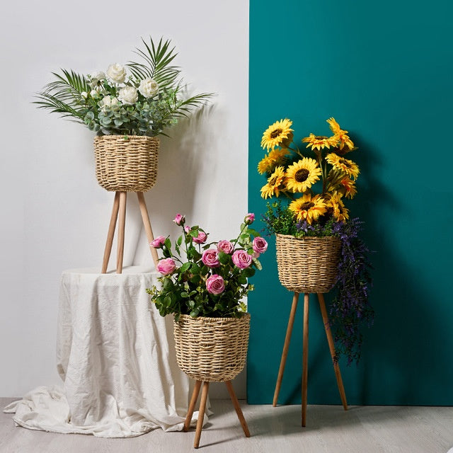 Small natural straw floor pot beside a bedroom window with a small potted plant inside
